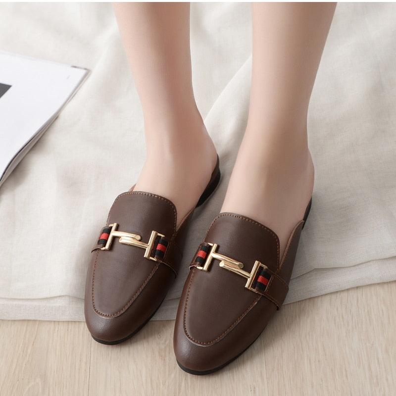 Classic brown leather pointed-toe mule flats with riveted details, shown from a top-down angle.
