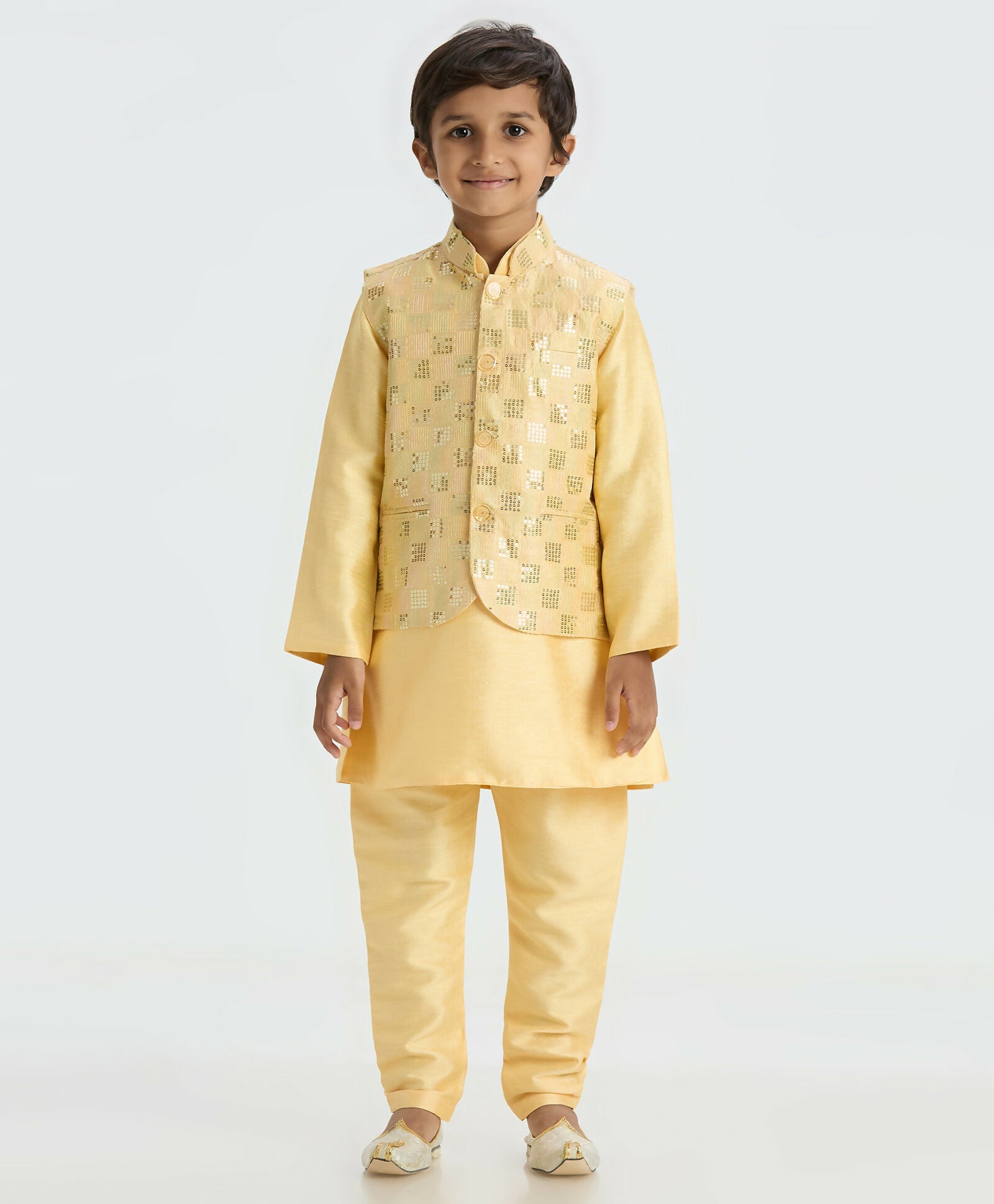Boy wearing a golden ethnic kurta pyjama set with a decorative Nehru jacket