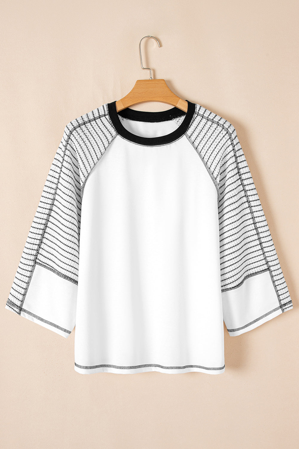 White long-sleeve top featuring black and white striped raglan sleeves and a solid white center panel on a hanger.