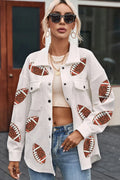 A woman wearing a white collared jacket with sequin football patches, buttoned down with snap closures.