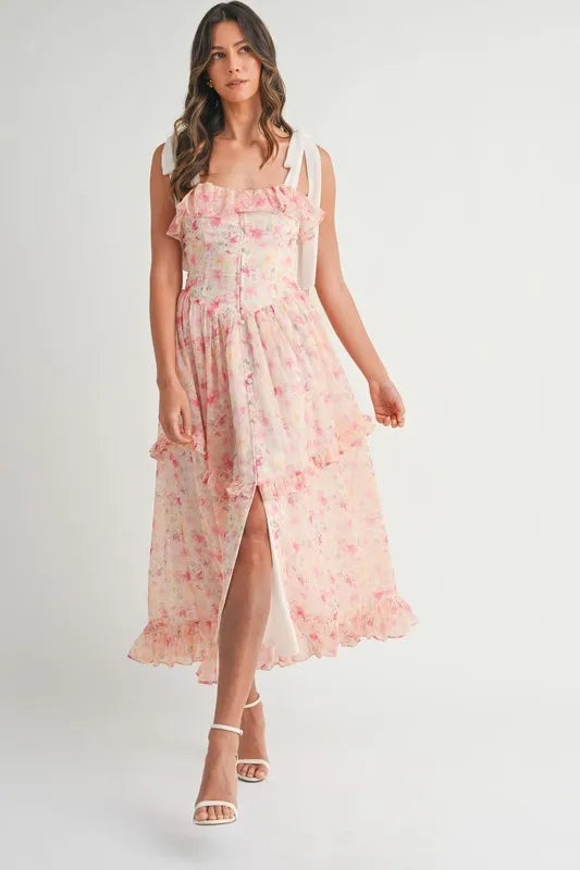 Woman wearing a floral print chiffon midi dress with shoulder straps and ruffled details