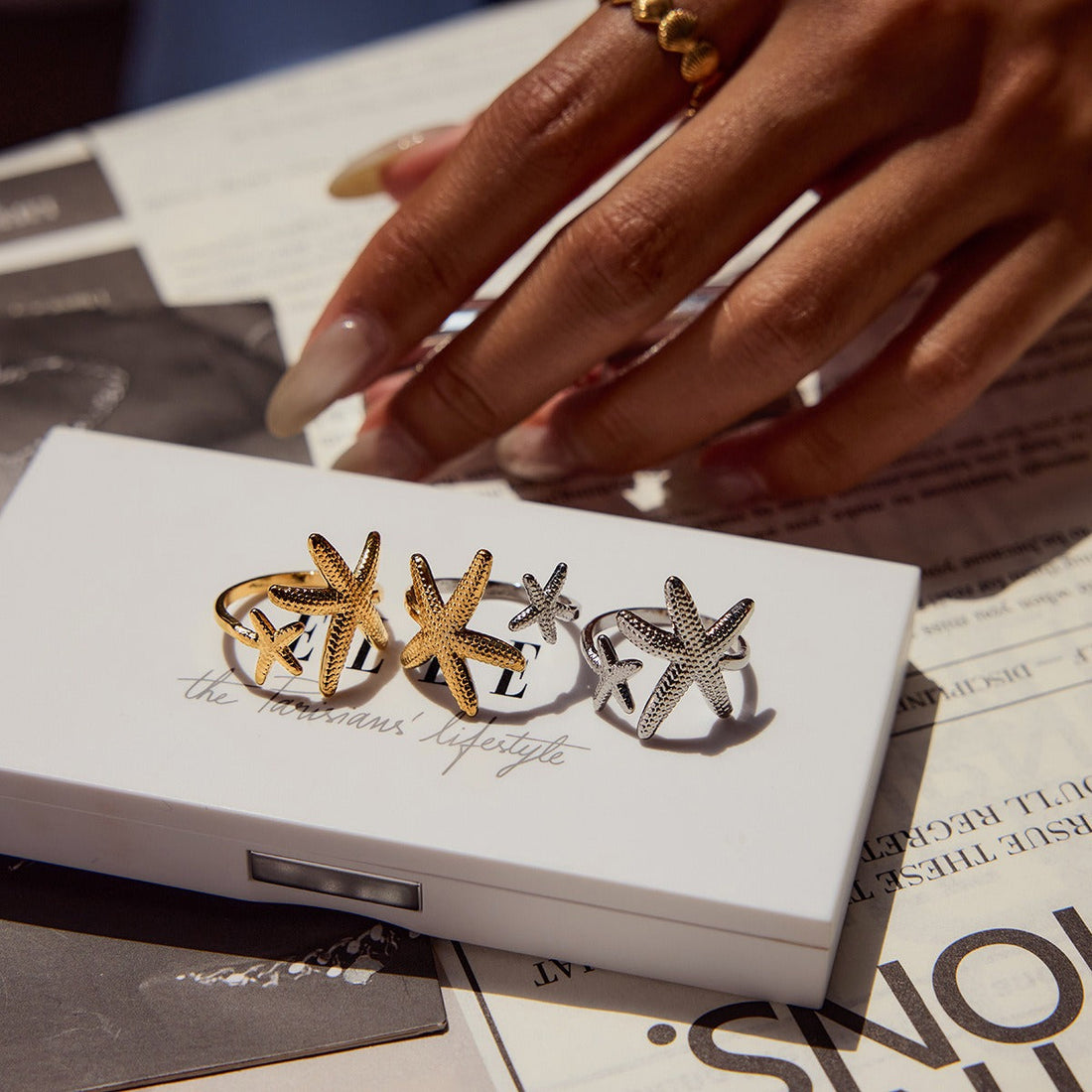 Close-up of a gold starfish and shell-themed adjustable titanium steel ring on a woman's hand.