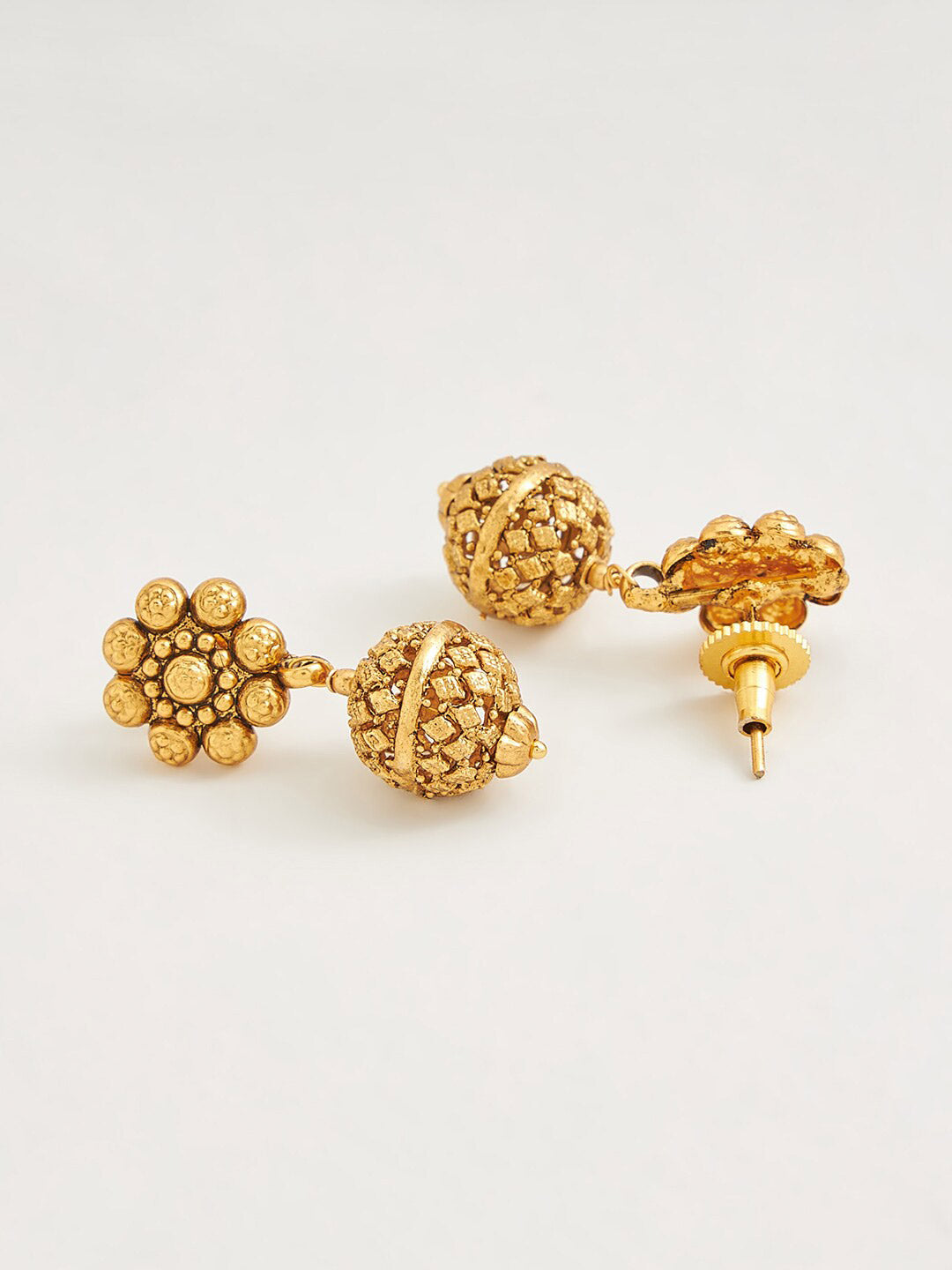 Close-up of an elegant gold-toned necklace and jewellery set on a neutral background