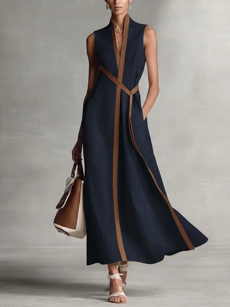 A woman wearing a sleeveless maxi dress with a stand collar and contrast color block vertical panel, available in deep navy or rich maroon.