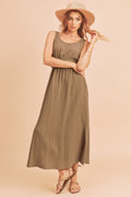 Woman wearing an olive green sleeveless cotton tank dress with a side slit detail.