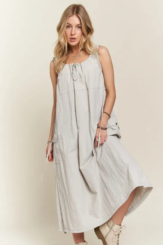 A stylish light grey and beige utility-style cargo dress with a drawstring waist and slit back.