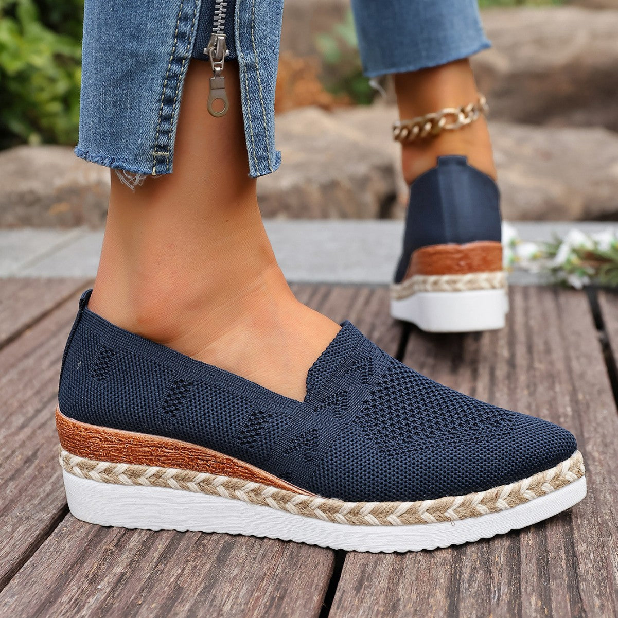 Close-up of a woman wearing navy blue knit platform slip-on loafers with an espadrille rope sole and wood-like wedge detail.