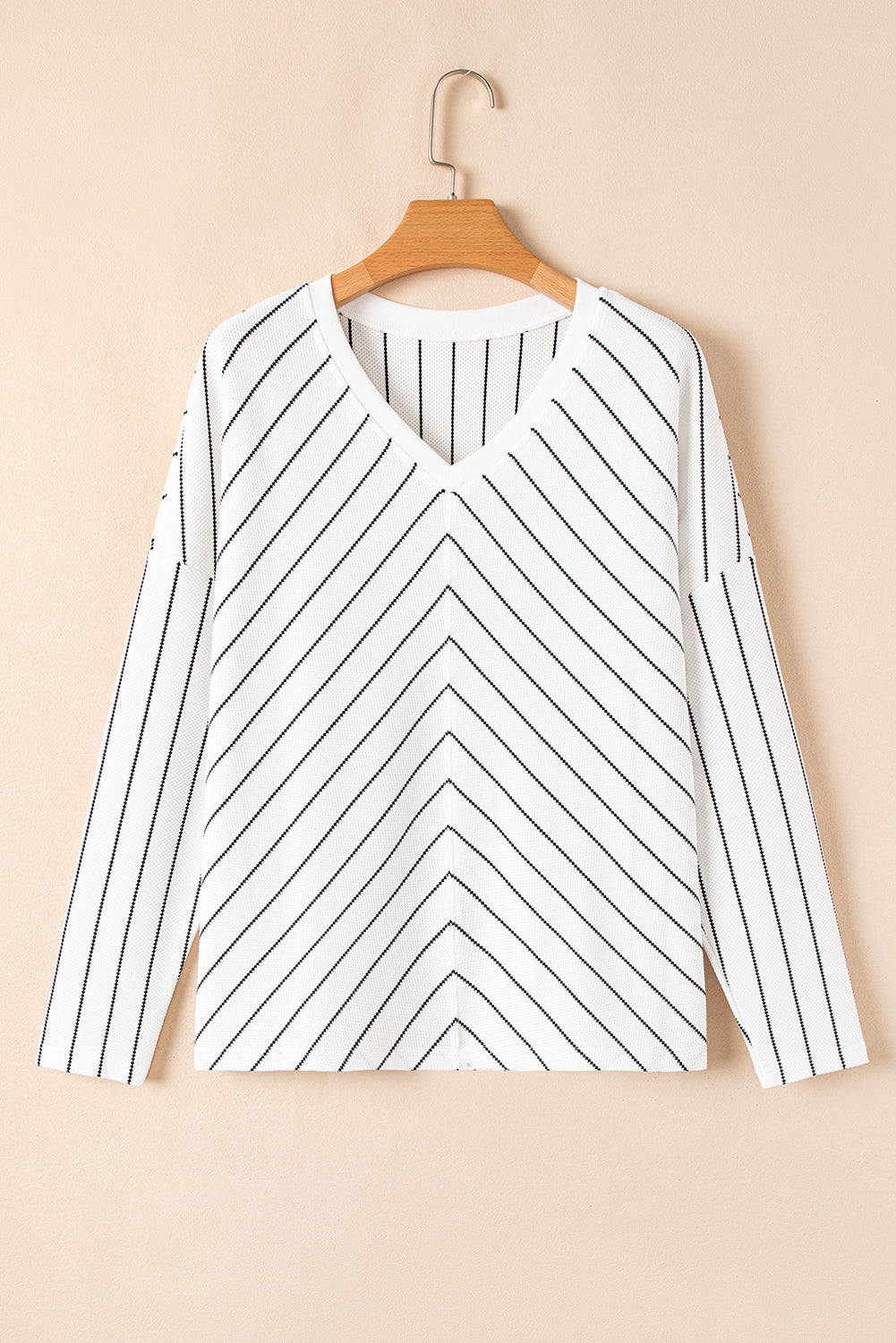 White long sleeve top with black chevron stripes and V-neckline displayed on a hanger