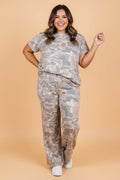 A woman wearing a two-piece camouflage print outfit consisting of a short sleeve tee and matching wide-leg pants.