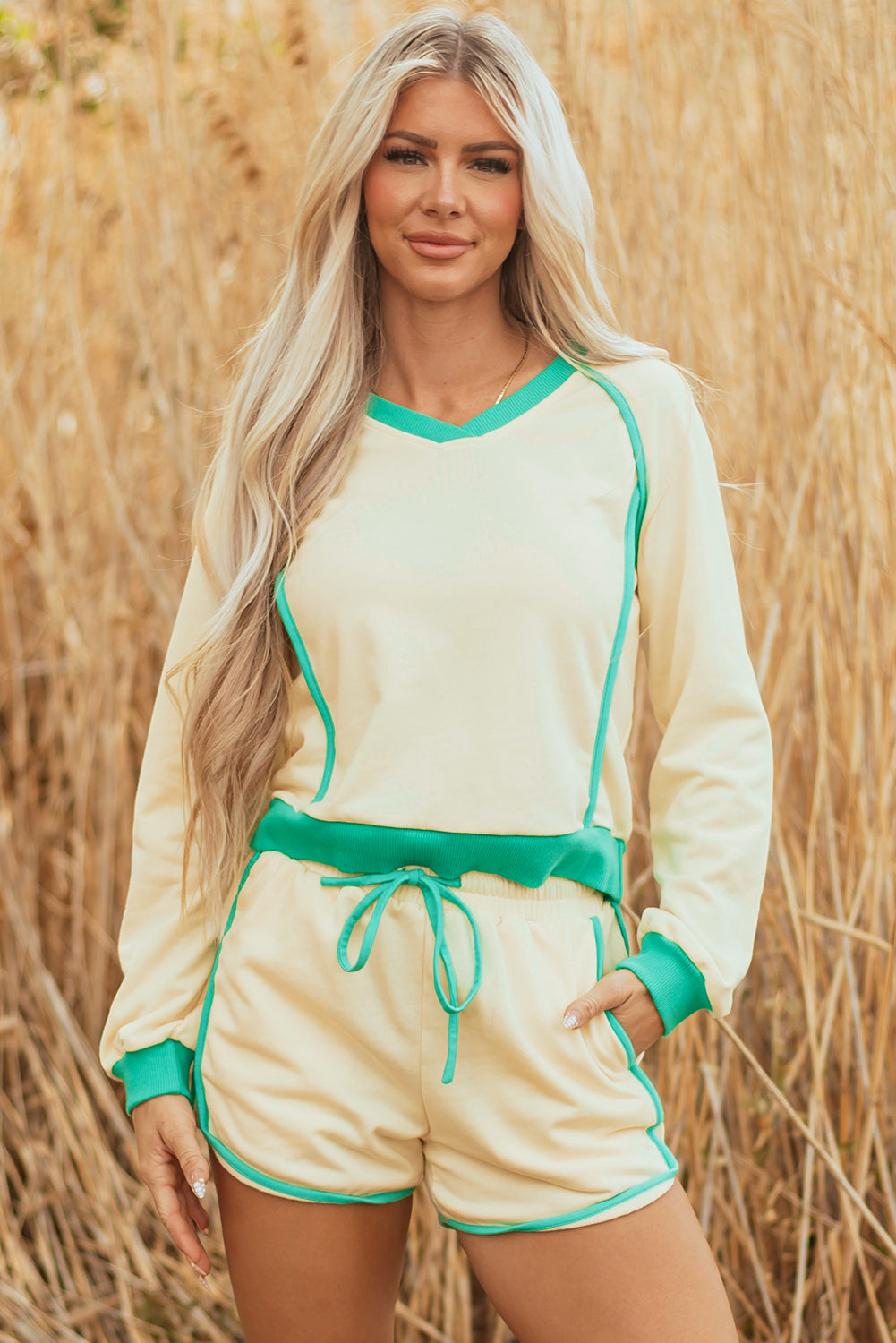 Model wearing a yellow long sleeve pullover and matching drawstring shorts set with green contrast piping