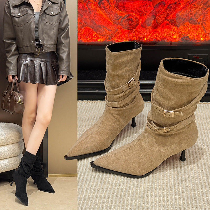 A pair of tan suede ankle boots with pointed toes and stiletto heels featuring decorative buckle straps, displayed next to a model wearing the same style in black.