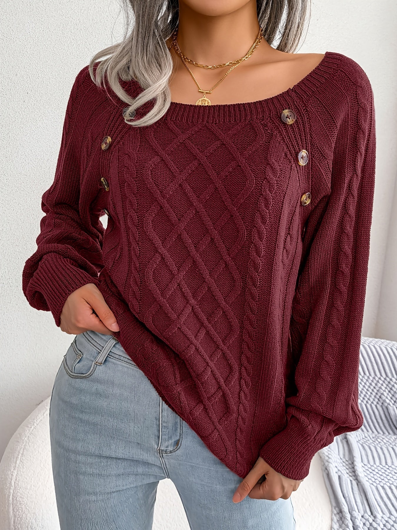 Close up of a woman wearing a textured cable knit sweater with decorative buttons and lantern sleeves