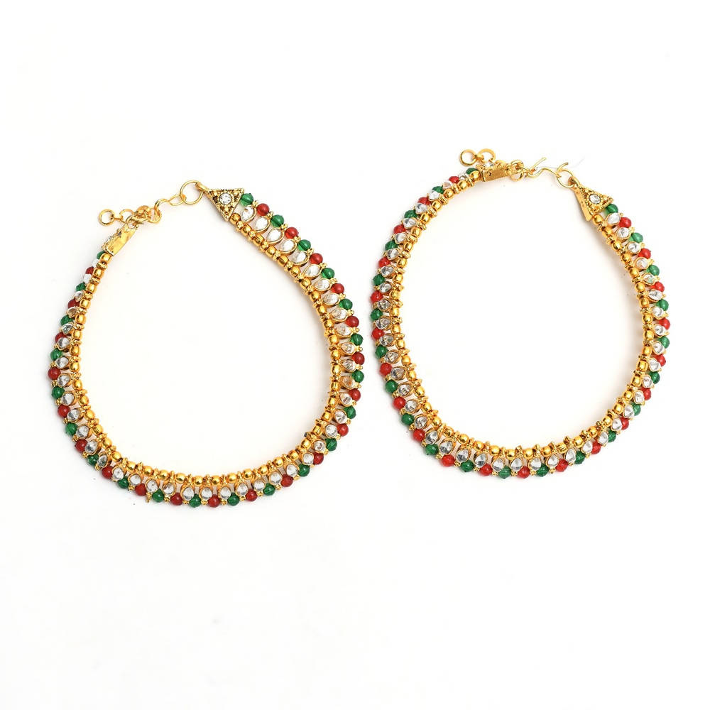 Close up of gold-plated multi kundan anklets with red, green, and white stones