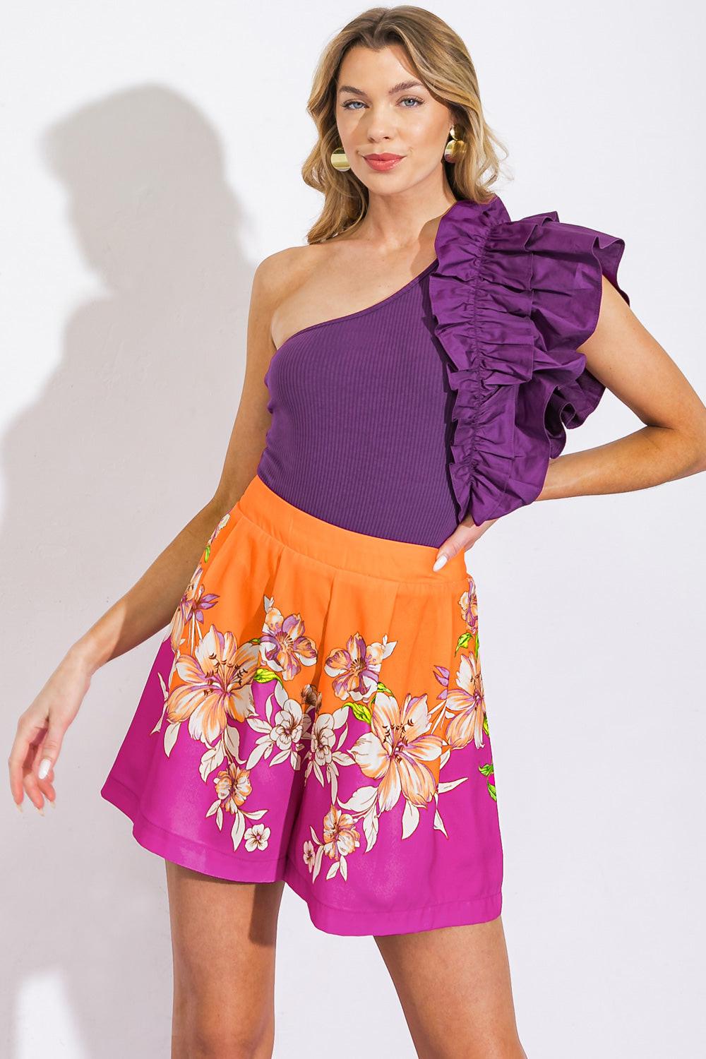 Back view of orange and magenta floral print pleated shorts with an elastic waistband