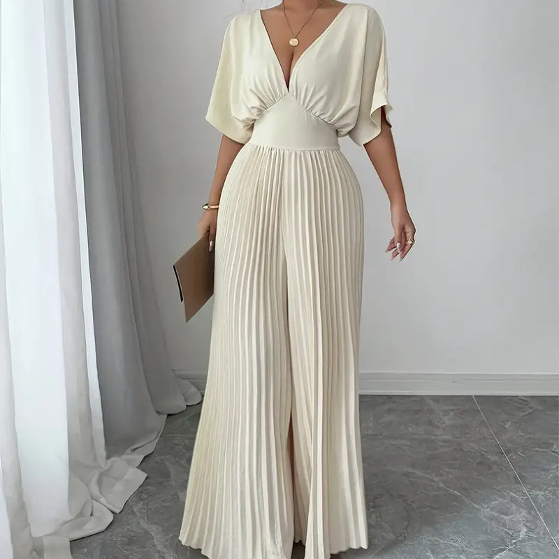 Model wearing a minimalist cream pleated V-neck shirt jumpsuit, highlighting the structured neckline and fluid polyester fabric.