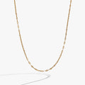 Gold multi faceted lip chain necklace resting on a neutral background, highlighting the light-catching texture.