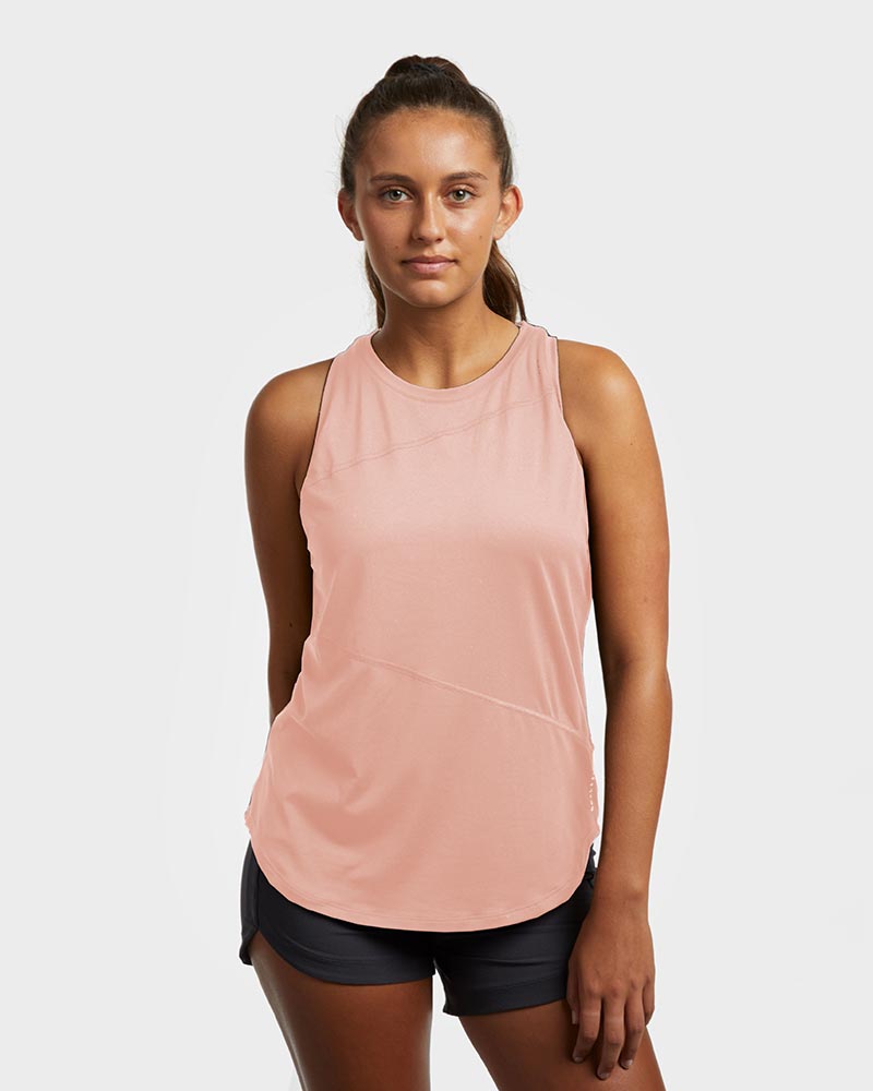 A woman wearing a pink athletic tank top with a racerback style, featuring moisture-wicking fabric and a curved hemline.