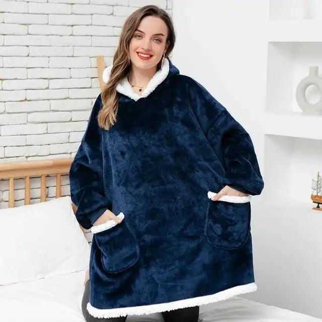 A person wearing a thick, oversized flannel blanket hoodie with sleeves for winter warmth.