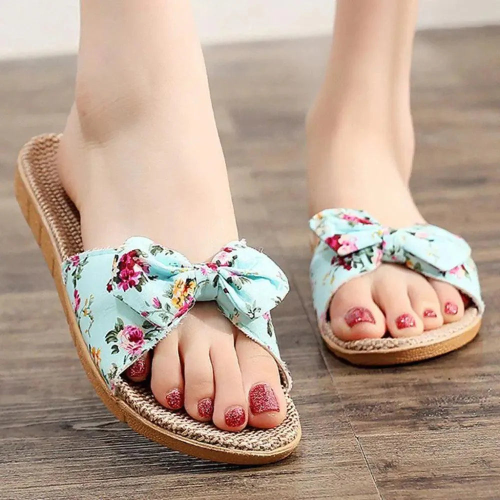 Women's floral flip-flops with butterfly knot detail in light-blue, pink, and tan.