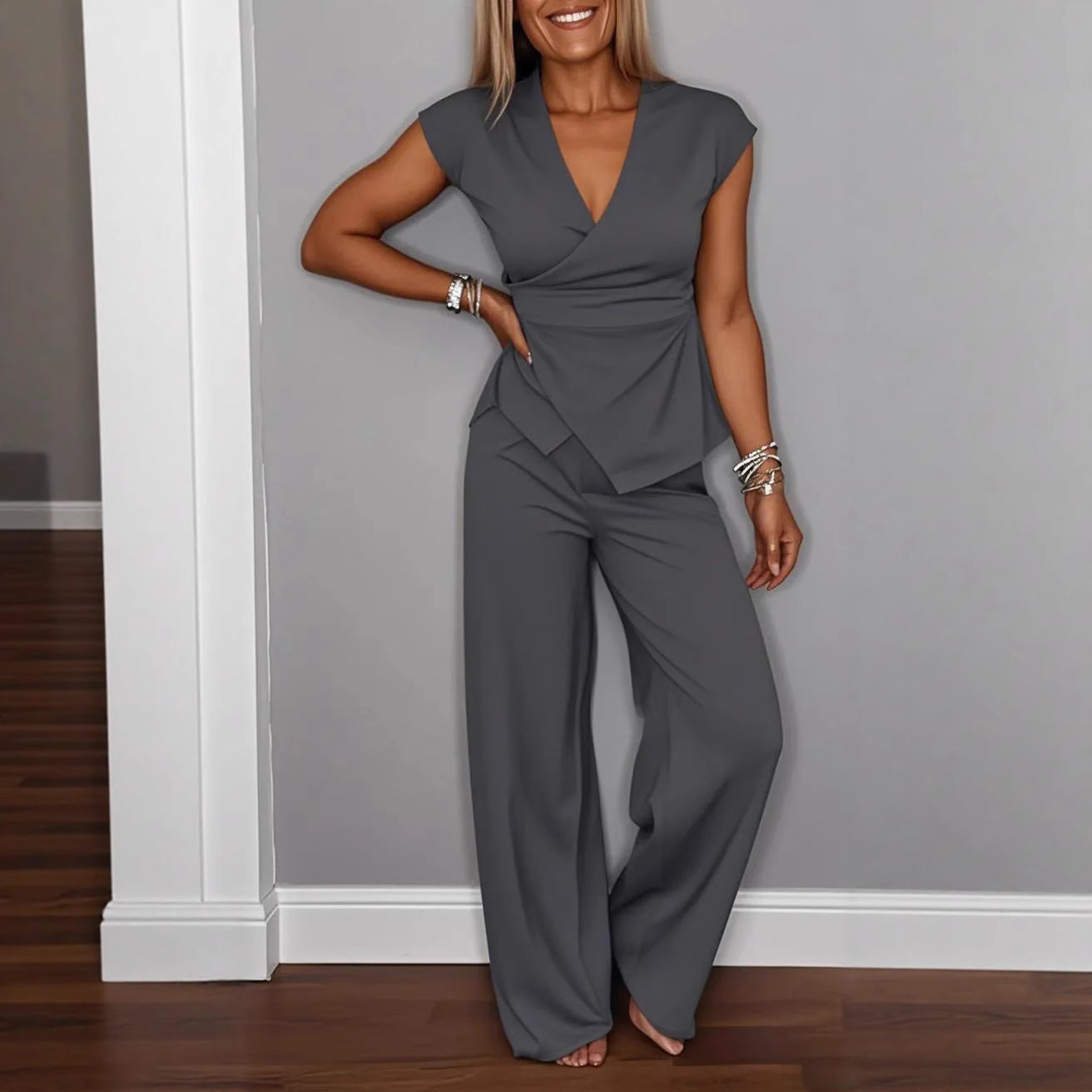 Model wearing a grey wrap vest and matching wide-leg trousers set with a silver buckle detail.