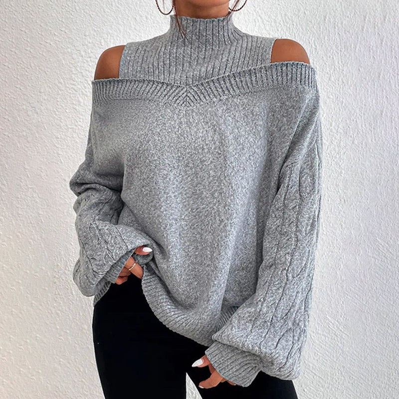Model wearing a grey long sleeve cold shoulder high neck cable knit sweater
