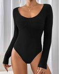 Black bodysuit with long sleeves worn by a model against a neutral background