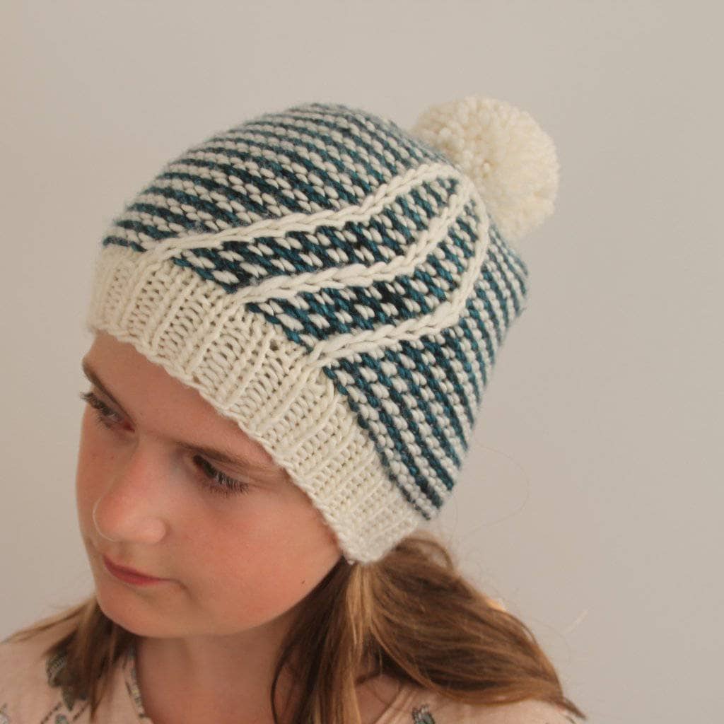 Close up of a hand-knit beanie hat made with the Feather In Your Cap knitting pattern