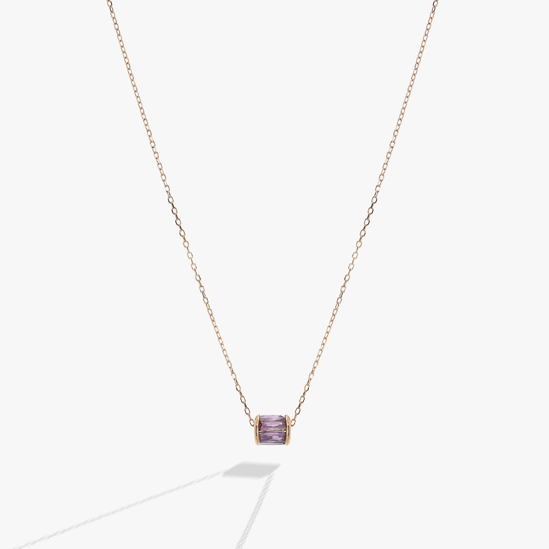 February birthstone necklace featuring a gold-plated barrel pendant with an amethyst-hued crystal on a fine cable chain.