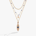 Three-strand gold layered necklace featuring a blue evil eye pendant, a puffy heart, and crystal accents.