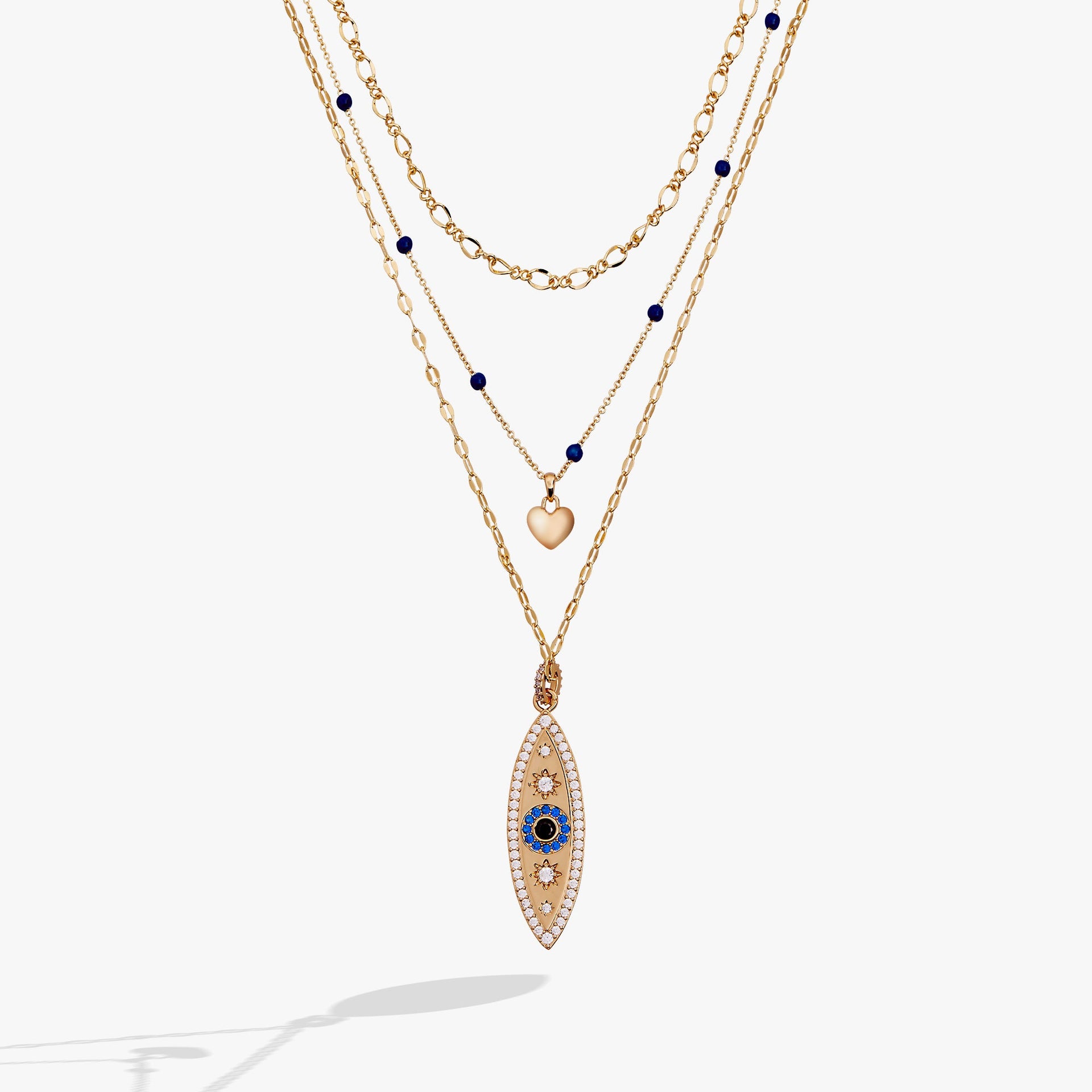 Three-strand gold layered necklace featuring a blue evil eye pendant, a puffy heart, and crystal accents.