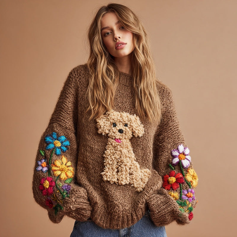 A woman wearing a brown crew neck knit sweater with a textured puppy graphic on the chest and colorful floral embroidery on the sleeves.