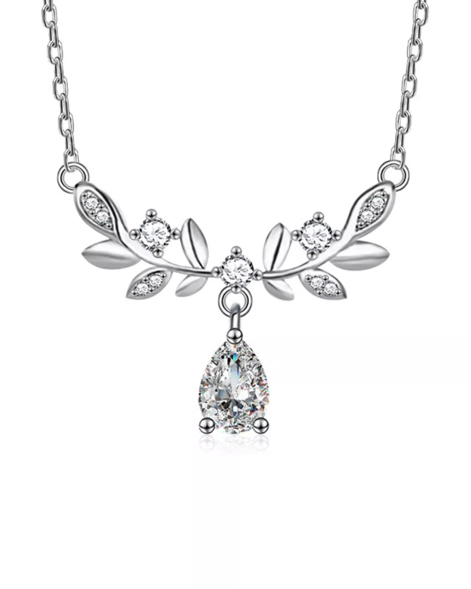Silver necklace with leaf design and teardrop pendant on a white background