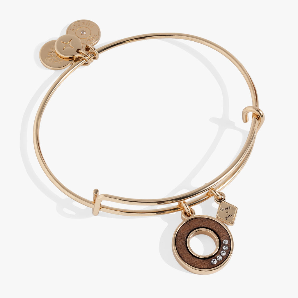 Five-year anniversary bangle featuring a circular wood-inlay charm and clear crystal accents