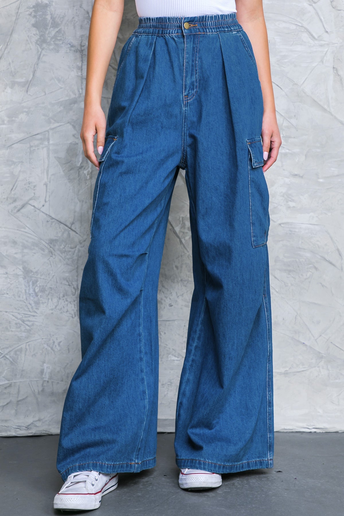 Model wearing wide leg washed denim cargo pants with elastic waist and side pockets