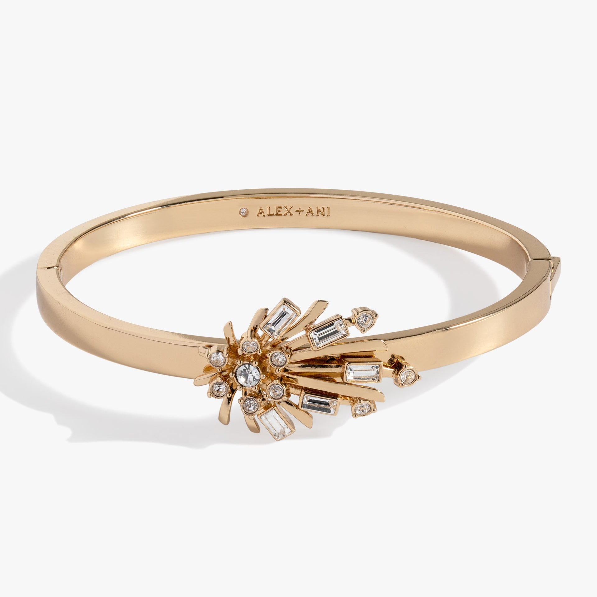 Gold-tone hinge bangle featuring a starburst emblem decorated with sparkling clear crystals.