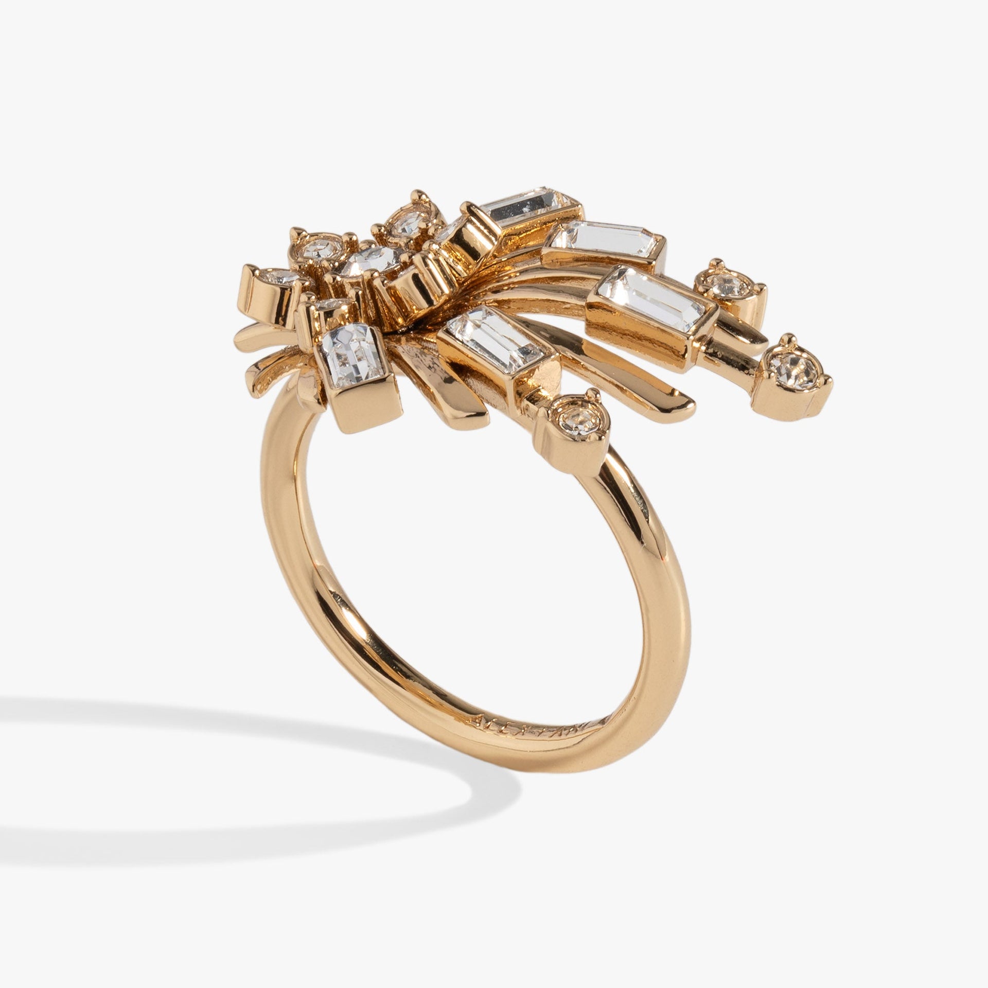 Gold-tone starburst statement ring featuring clear crystal accents on a white background