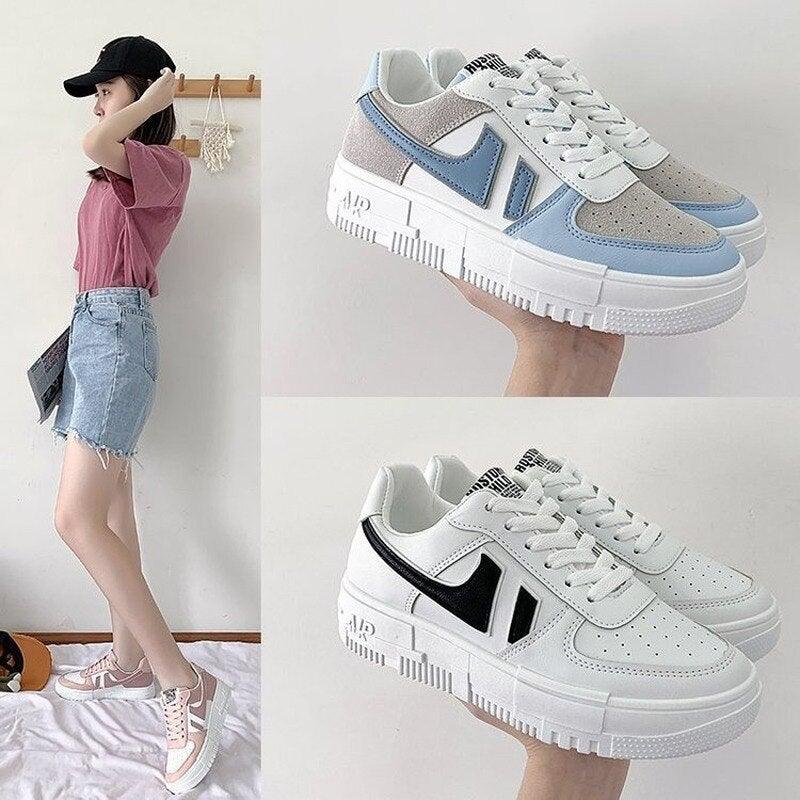A pair of classic women's white low-top lace-up sneakers on a neutral background