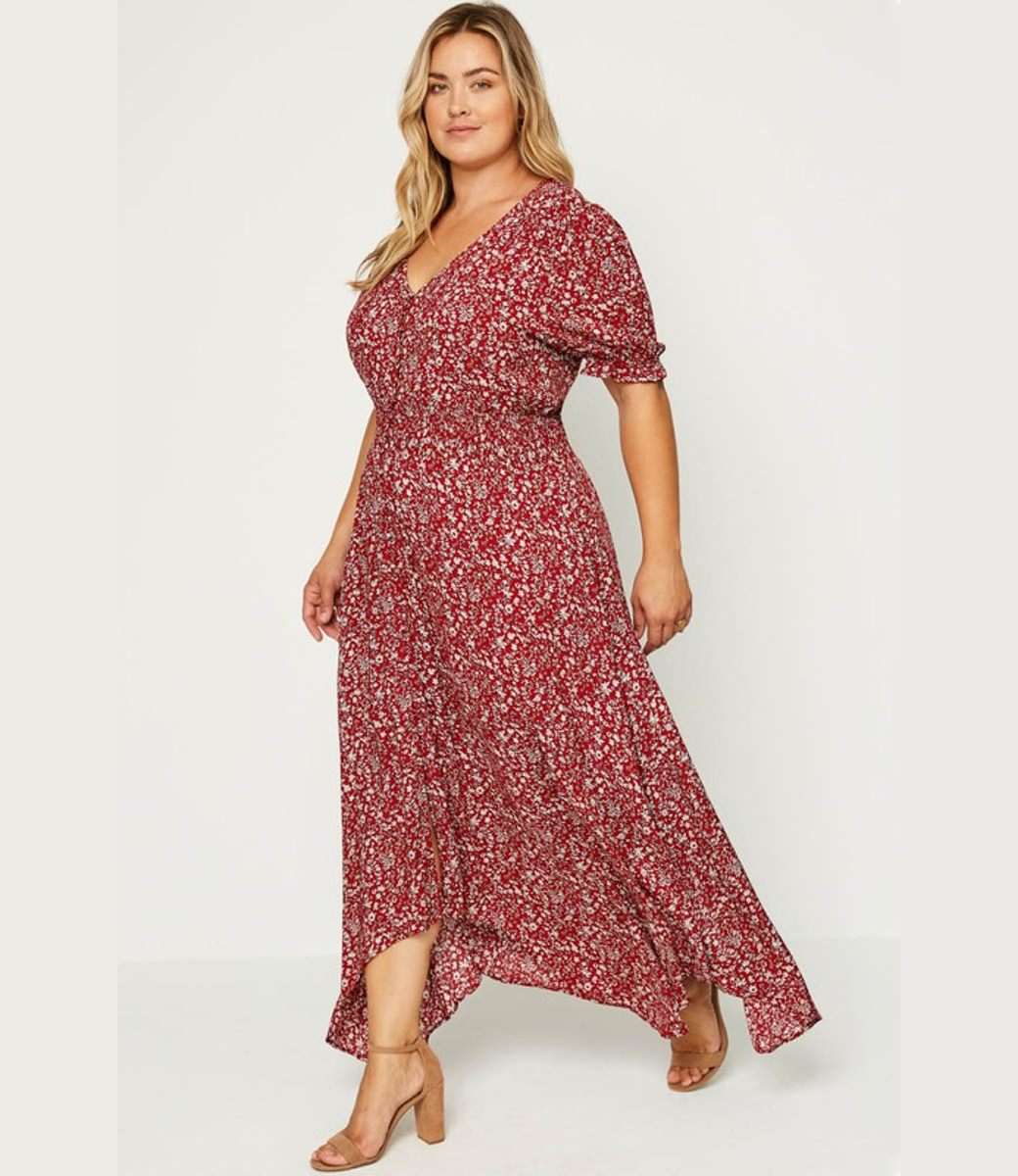 A woman wearing a red floral maxi dress with a V-neck, short puff sleeves, and a ruched smocked waist.