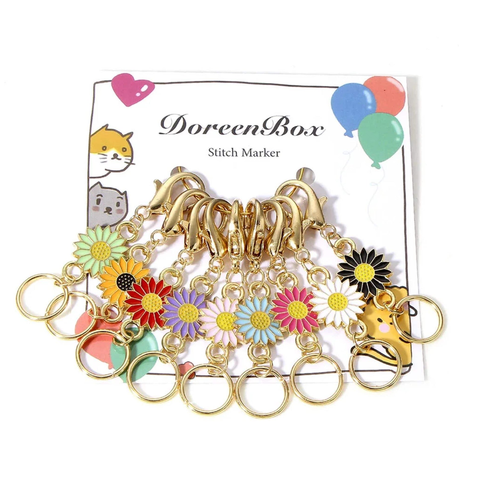 Multi-color floral enamel stitch markers with gold-tone lobster clasp hardware on a craft table.