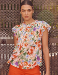 A woman wearing a red flutter sleeve blouse with floral print and ruffled shoulder detail, viewed from the front.