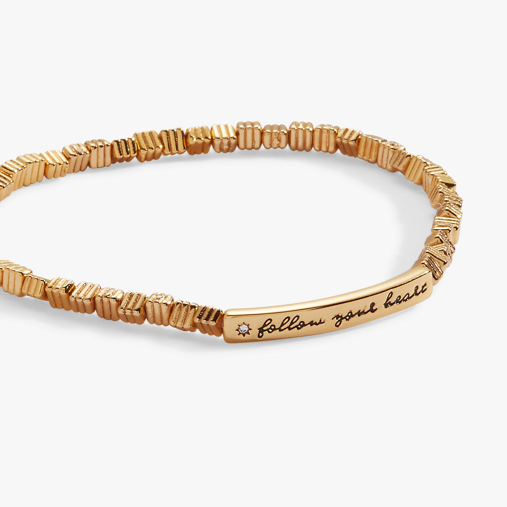 Minimalist stretch bracelet featuring a beaded band and engraved Follow Your Heart plate with crystal star