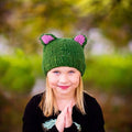 Forest Friends wool hat knitting pattern shown in forest green and magenta-pink colorways.