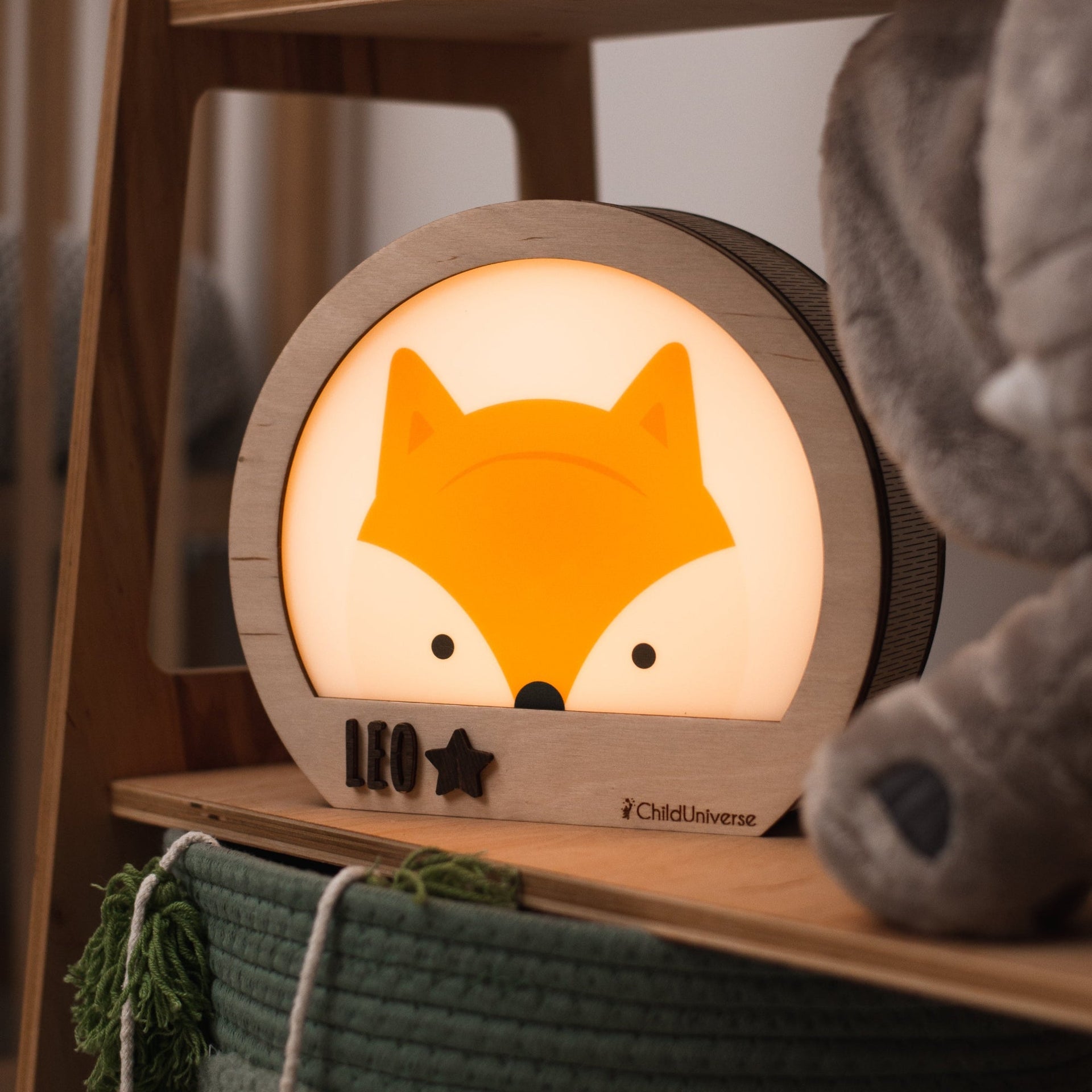 A cute fox-shaped night light glowing softly on a nursery bedside table.