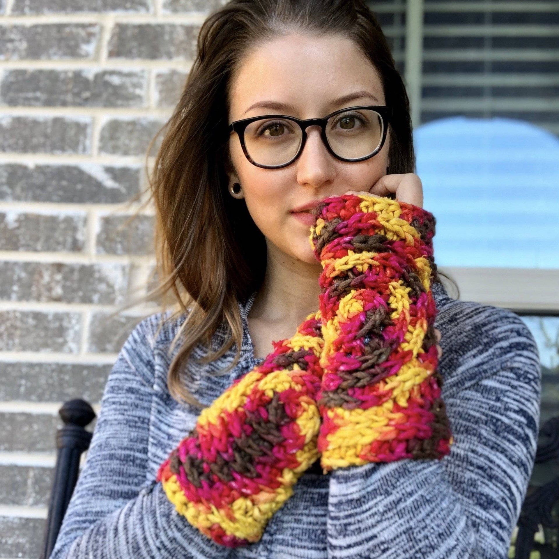 Close up of bohemian freeform crochet fingerless mittens in yellow, magenta, and brown yarn with a spiral pattern.