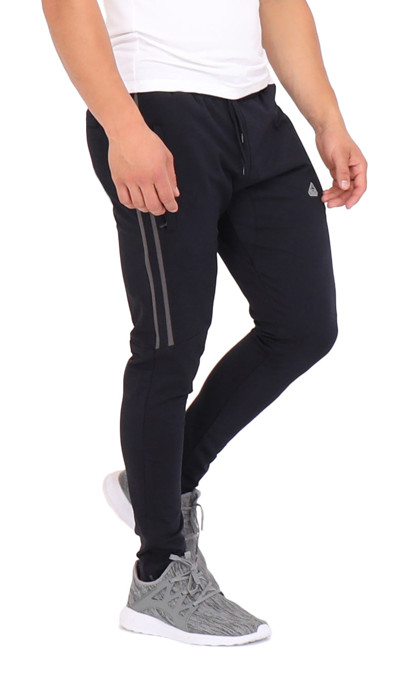 A man wearing black performance joggers with side stripe detail and zippered leg openings.