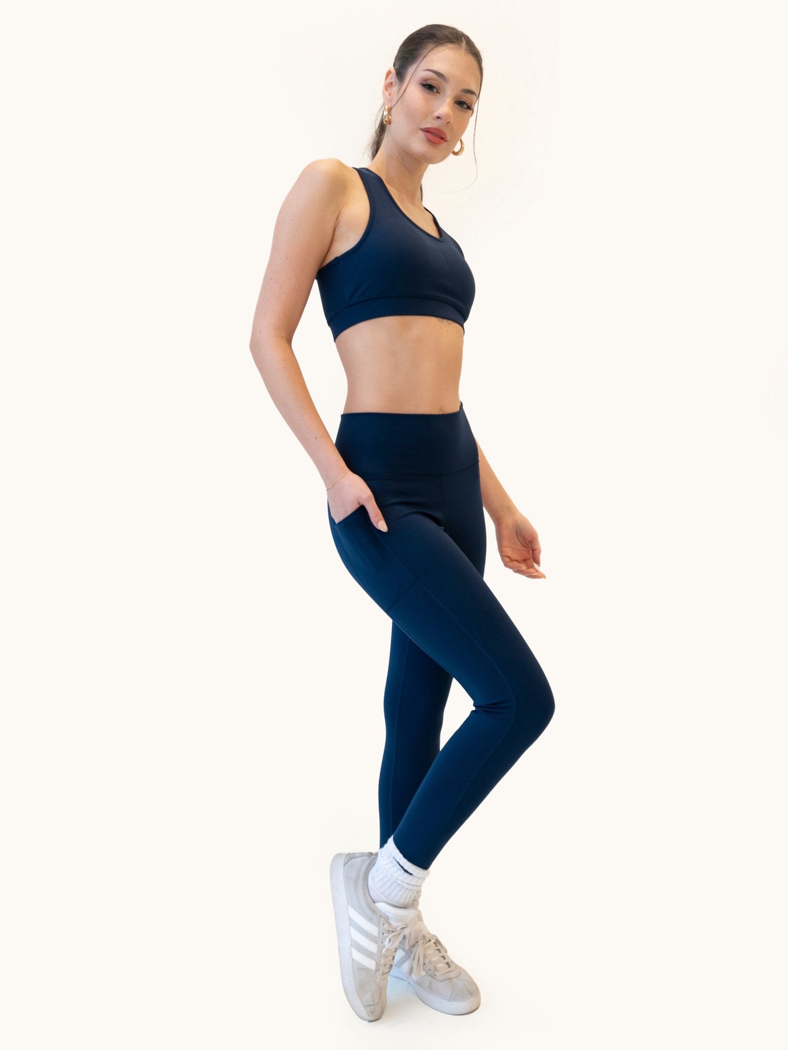 Model wearing dark navy blue high-waisted performance leggings with side pockets