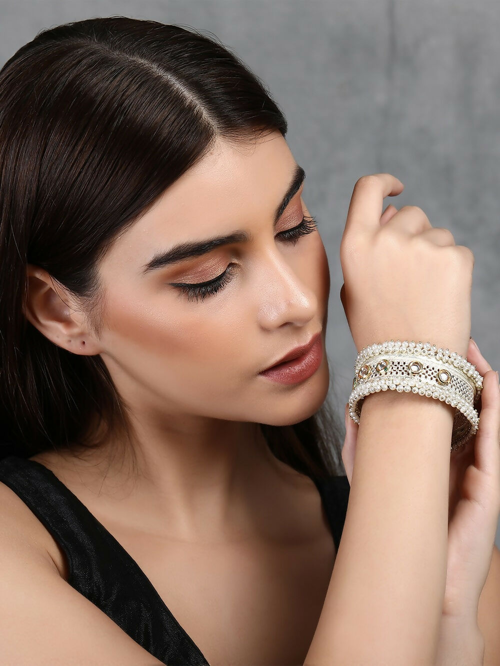Close-up view of a handcrafted silver tone bangle with white beads and sparkling stones.