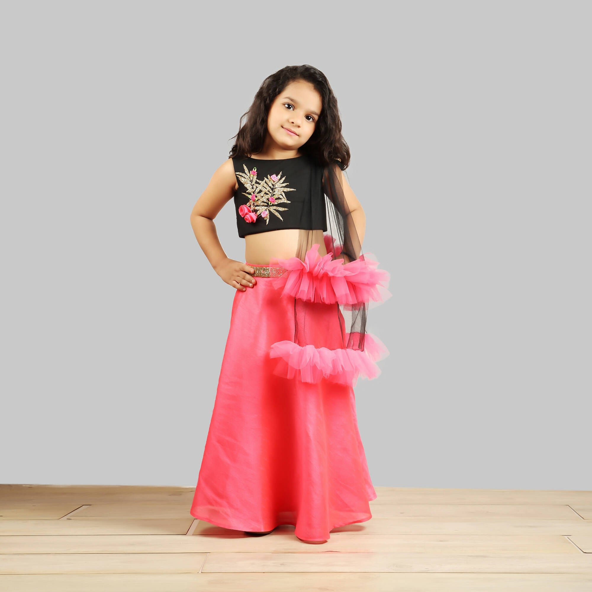Black choli with gold patch and pink ghagra paired with a frill-trimmed net dupatta