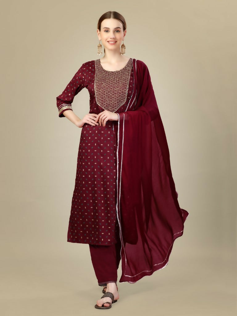 A woman wearing a maroon silk blend kurta with intricate embroidery and sequence work, paired with matching trousers and a dupatta.