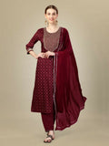 A woman wearing a maroon silk blend kurta with intricate embroidery and sequence work, paired with matching trousers and a dupatta.